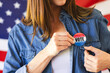 © Wavebreak Media - A middle-aged caucasian woman pins a vote badge on her denim shirt