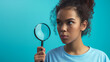 Teen with a contemplative expression holding a magnifying glass over her shoulder, wearing a pastel blue shirt, symbolizing the scrutiny required in early detection of skin conditions
