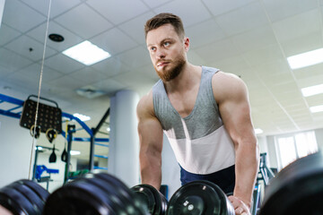 Wall Mural - Handsome young man with beard is engaged in gym