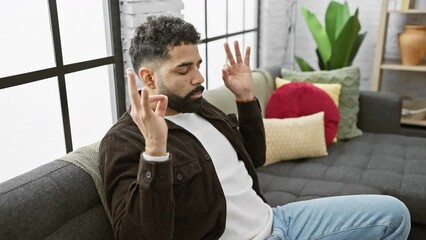 Wall Mural - Young, confident arab man finds happiness in a peaceful meditation session, eyes closed, executing a yoga gesture, hands revealing the beauty of relaxation at home.