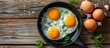 Three eggs are sizzling in a frying pan on a rustic wooden table, creating a delicious aroma. These eggs are a key ingredient in many recipes and are a versatile food staple in various cuisines