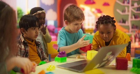 Wall Mural - Cute Caucasian, Asian and African Kids Playing Together with Colorful Building Blocks. Smart Adorable Children Using Laptop Computer to Watch Educational Videos and Tutorials for Building Toy Castles