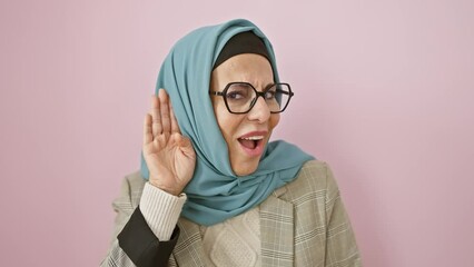 Canvas Print - Heartwarming sight of a middle age, hispanic woman happily wearing hijab, hand over ear, getting the lowdown on juicy gossip. deafness isn't stopping her! on a vibrant isolated pink background.