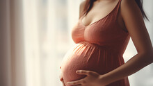 A Pregnant Woman Holds Her Already Enlarged Belly, Close-up View Of The Belly, Blurred Hospital Background