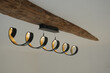 Black and bronze spiral chandelier hanging from an oak beam on a white plasterboard ceiling. Light on. 