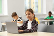 © New Africa - Smiling little girl with laptop studying in classroom at school