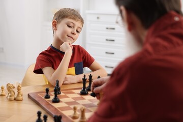 Poster - Little boy playing chess with his grandfather at table in room