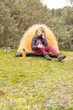 Curly and blonde hair, mountaineer woman camps with his orange tent and using his smart phone