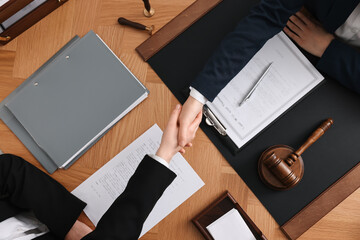 Canvas Print - Notary shaking hands with client at wooden table, top view