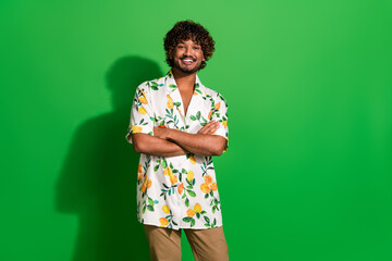 Wall Mural - Photo of cheerful good mood arabian man wear print shirt arms folded empty space isolated green color background