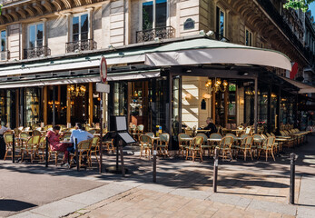 Wall Mural - Typical view of the Parisian street with tables of brasserie (cafe) in Paris, France. Cozy cityscape of Paris. Architecture and landmarks of Paris.