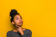 Young smiling pensive wistful nice brunette African American positive cute woman 20s wearing casual prop up chin look aside isolated on plain light yellow color background studio portrait