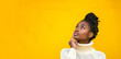 Young smiling pensive wistful nice brunette African American positive cute woman 20s wearing casual prop up chin look aside isolated on plain light yellow color background studio portrait