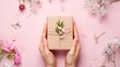 Hands presenting a handmade gift with delicate spring flowers and craft packaging. The tender act of giving captured in a simple yet elegant floral gift box.