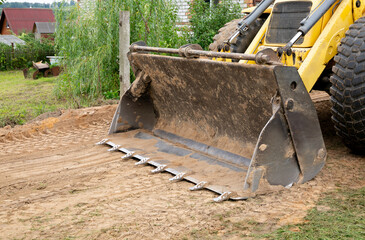 Wall Mural - Large wide bucket with metal teeth of heavy front loader or bulldozer close-up. Copy space. Transportation and movement of bulk materials. Excavator shovel. Attachments