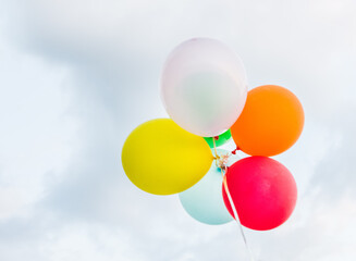 a bunch of colorful balloons with cloudy skies