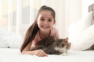 Wall Mural - Cute little girl with cat lying on bed at home. First pet