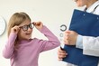 Vision testing. Little girl trying glasses at ophthalmologist office