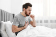 © New Africa - Sick man coughing on bed at home. Cold symptoms
