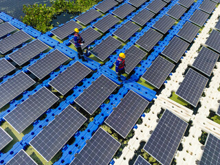 Top aerial of Male workers repair Floating solar panels on water lake. Engineers construct on site Floating solar panels. clean energy for future living. Industrial Renewable energy of green power.