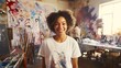 Smiling young African American woman painter with curly hair next to her artwork in an art studio. Concept of artistic talent, fine arts, creative process, oil painting, and cultural diversity.