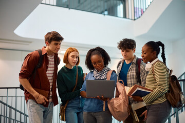 Wall Mural - Black student and her college friends using laptop in hallway.