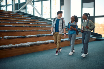 Wall Mural - Happy students communicating while leaving amphitheater after lecture at university.