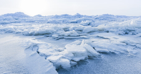 Wall Mural - Ice hummocks covered with snow. Panoramic landscape photo with coast of frozen Baltic Sea on cold winter day