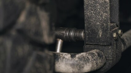 Poster - A mechanic tightens bolts with a wrench on the units and parts of a truck in a repair shop. Close-up.