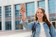 © Natalya - Vibrant college student taking a selfie in front of the university building