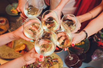 Wall Mural - Human hands with glasses of red wine clinking them over served table.