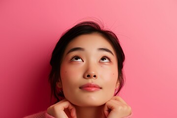 Wall Mural - Content Asian girl thinking and looking up on pink background contemplating the future