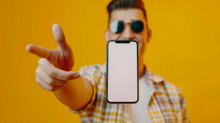 Human model in yellow studio background showing cellphone with empty screen spcae for business commercial.