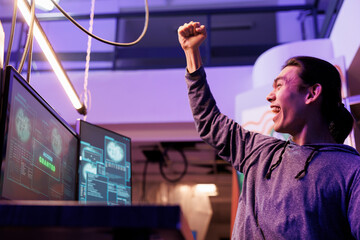 Poster - Happy hacker making victory gesture after getting server access granted. Cheerful excited asian man celebrating hacking computer network system successfully and raising fist