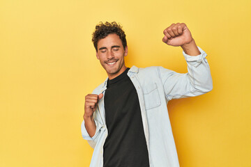 Wall Mural - Young Latino man posing on yellow background celebrating a special day, jumps and raise arms with energy.