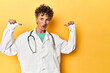 Caucasian mid-age female doctor on yellow studio feels proud and self confident, example to follow.