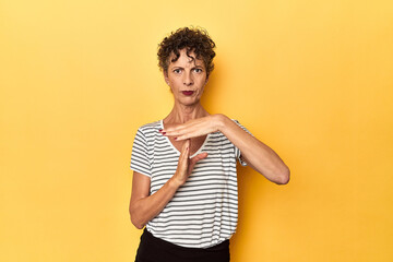 Wall Mural - Mid-aged caucasian woman on vibrant yellow showing a timeout gesture.