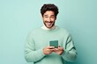 fun young man wear knitted sweater hold in hand use mobile cell phone look aside on workspace isolated on plain pastel light blue cyan background studio portrait - generative ai