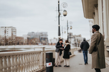 Wall Mural - A dapper businessman in a chic overcoat and hat stands absorbed in a phone conversation on an urban sidewalk, with passersby in the background.