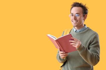 Canvas Print - Male student with book on yellow background