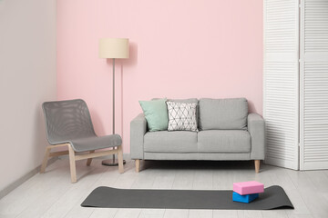 Poster - Interior of living room with sofa, chair and yoga equipment