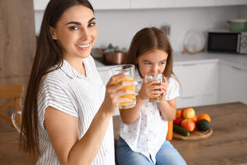 Canvas Print - Little girl with her mother drinking juice in kitchen