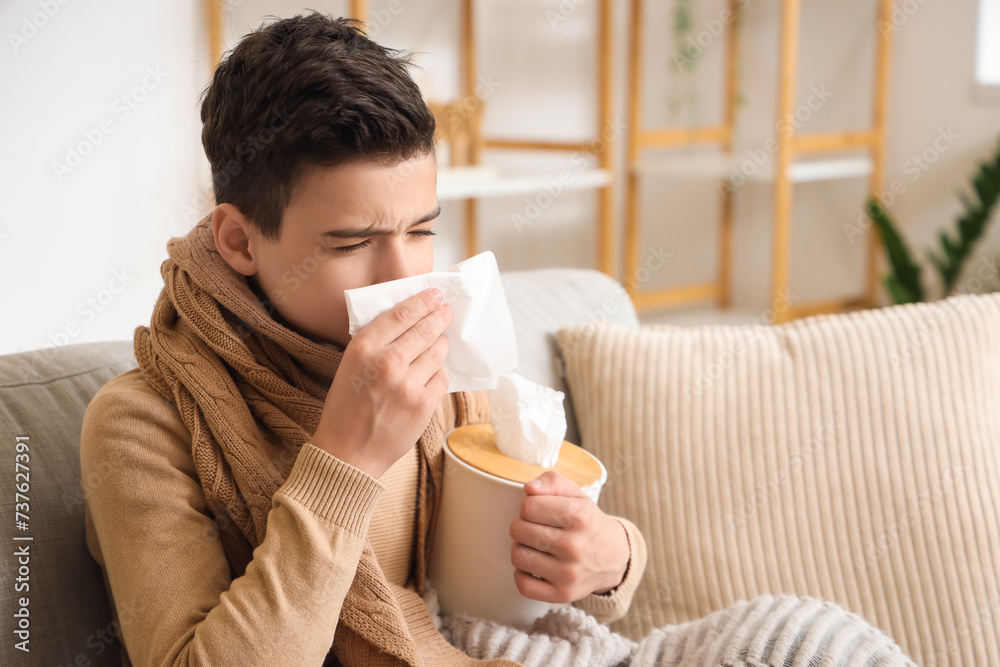 Sick little boy with tissue sneezing at home