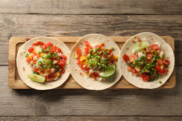 Wall Mural - Delicious tacos with vegetables, green onion, lime and ketchup on wooden table, top view