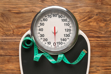 Scales with measuring tape on wooden background