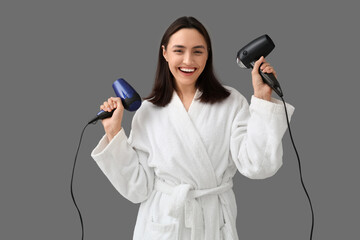 Wall Mural - Beautiful young woman with hair dryers on grey background