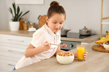 Canvas Print - Cute little girl eating cereal rings with orange juice at home