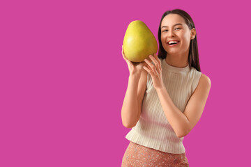 Canvas Print - Smiling young woman with pomelo on purple background