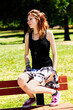 Young Caucasian Redhead Teen Girl Sitting On Back Of Park Bench