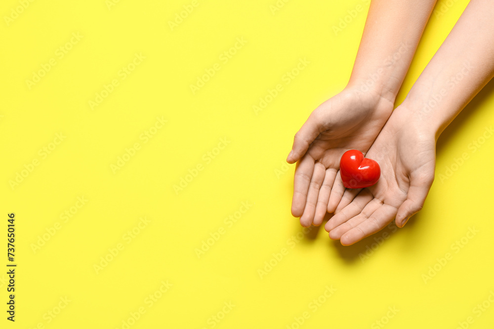 Female hands with red heart on yellow background